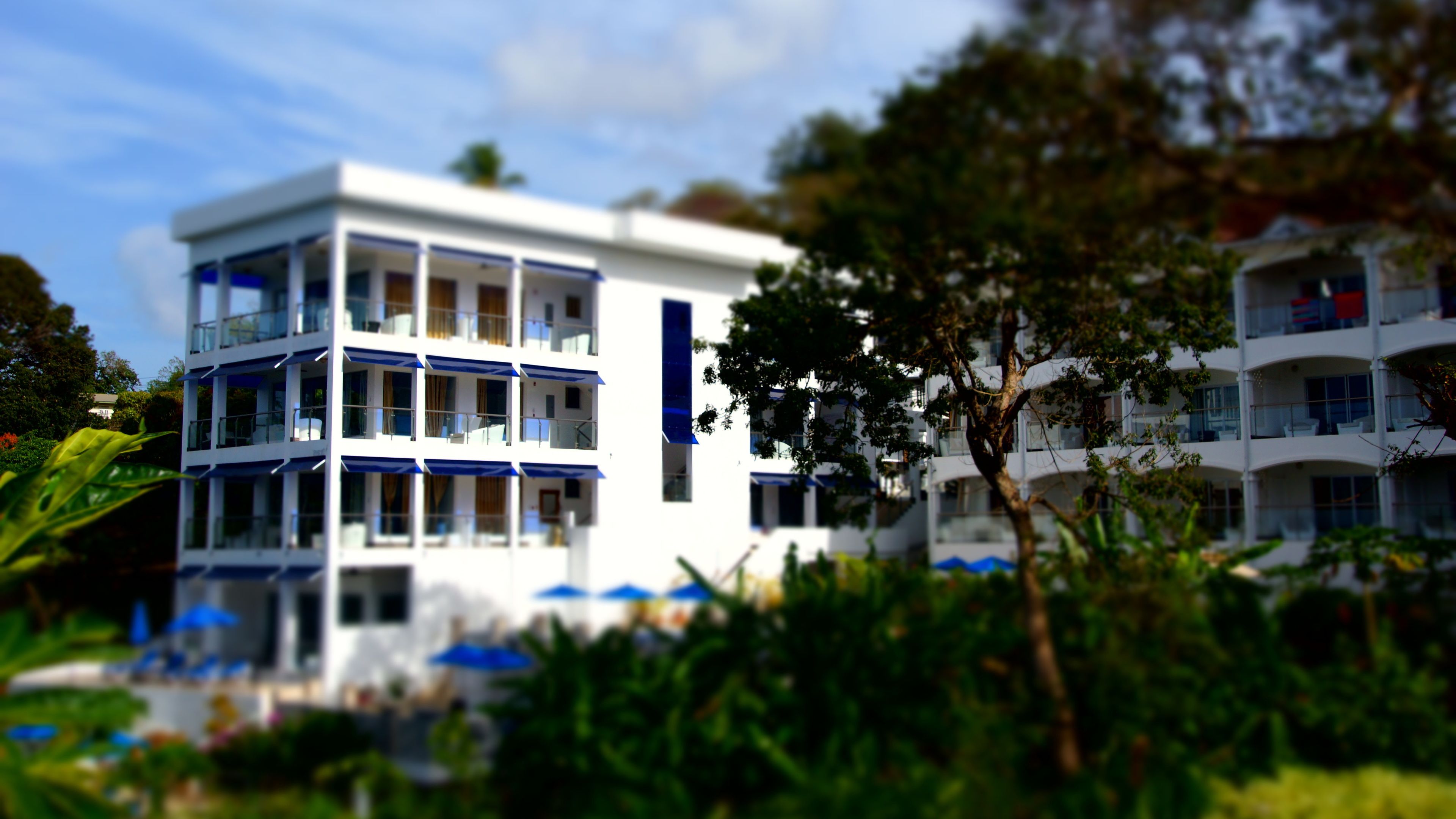 Un hotel de varios pisos con balcones y mesas al aire libre.