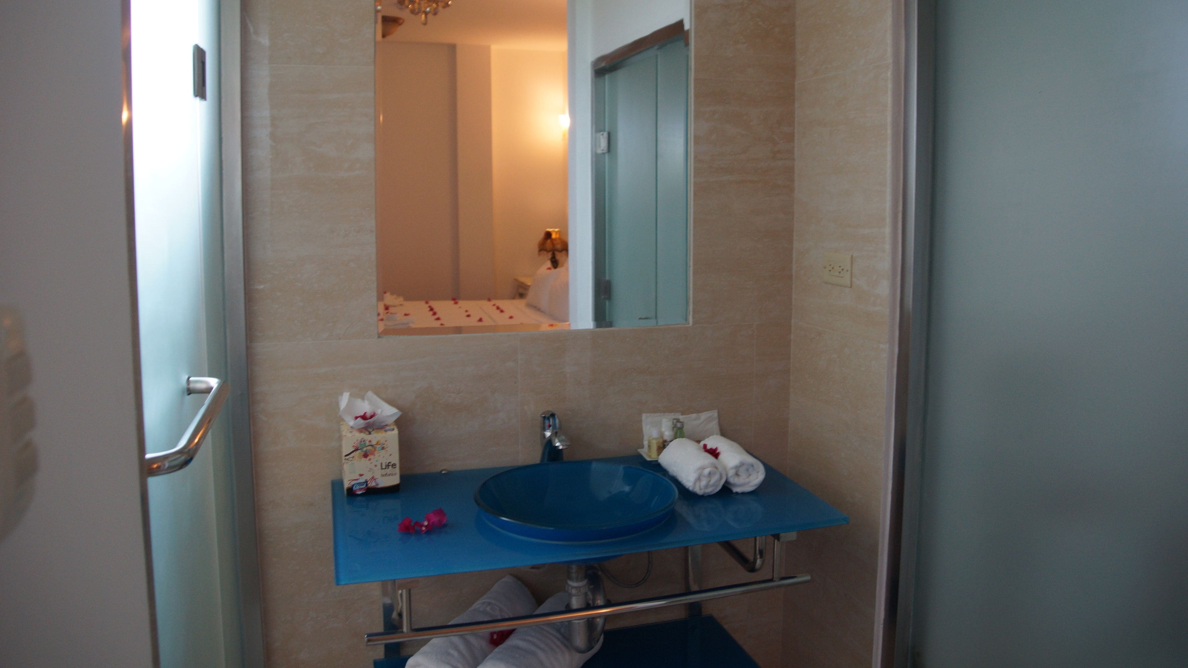 A bathroom with a blue sink, a mirror above it, and a towel rack.