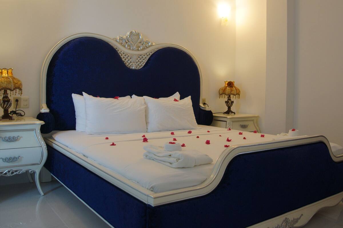 A bed with white linens, a decorative headboard, and two bedside tables with lamps.
