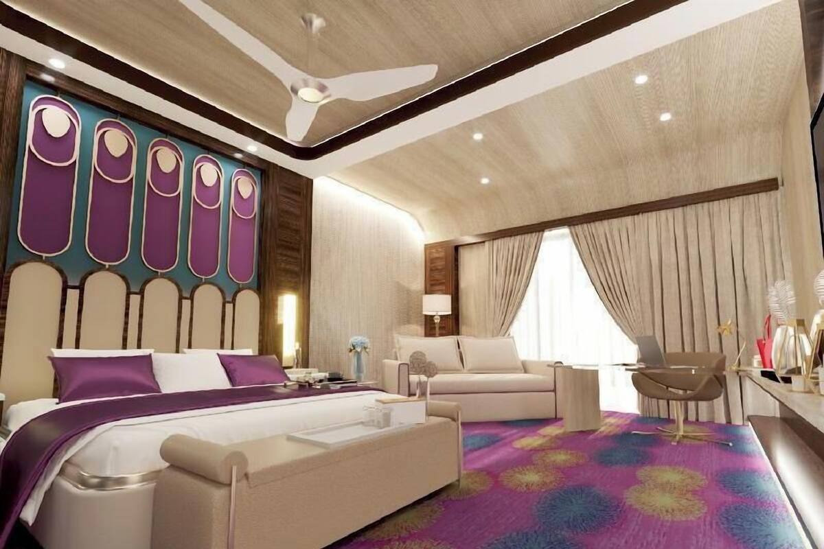 Una habitación de hotel moderna con una cama grande, un sofá, un escritorio y un ventilador de techo.