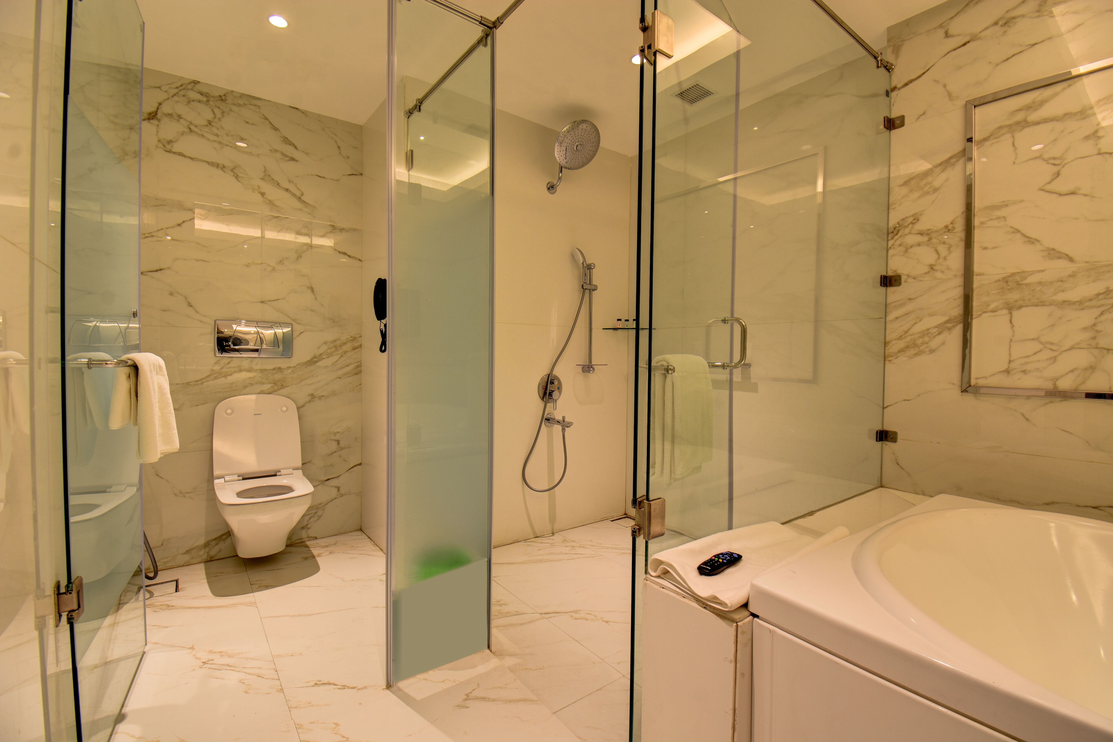 Une salle de bain moderne dotée d’une douche à parois de verre, de toilettes et d’une baignoire.