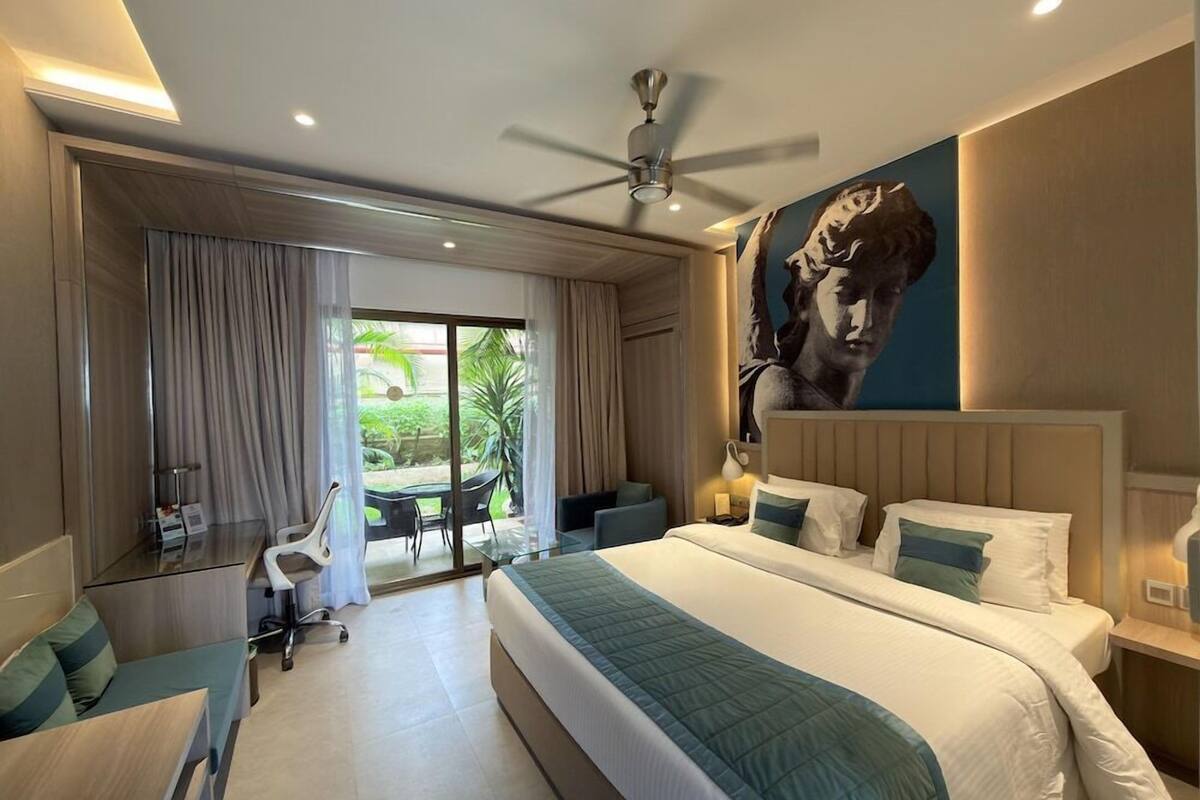 Habitación de hotel moderna con una cama grande, un escritorio y vistas al exterior.