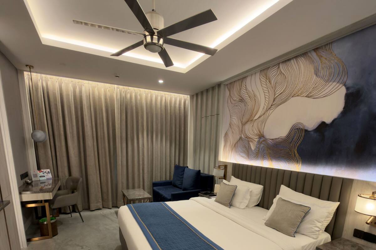 Una habitación de hotel moderna con una cama grande, un escritorio y un ventilador de techo.