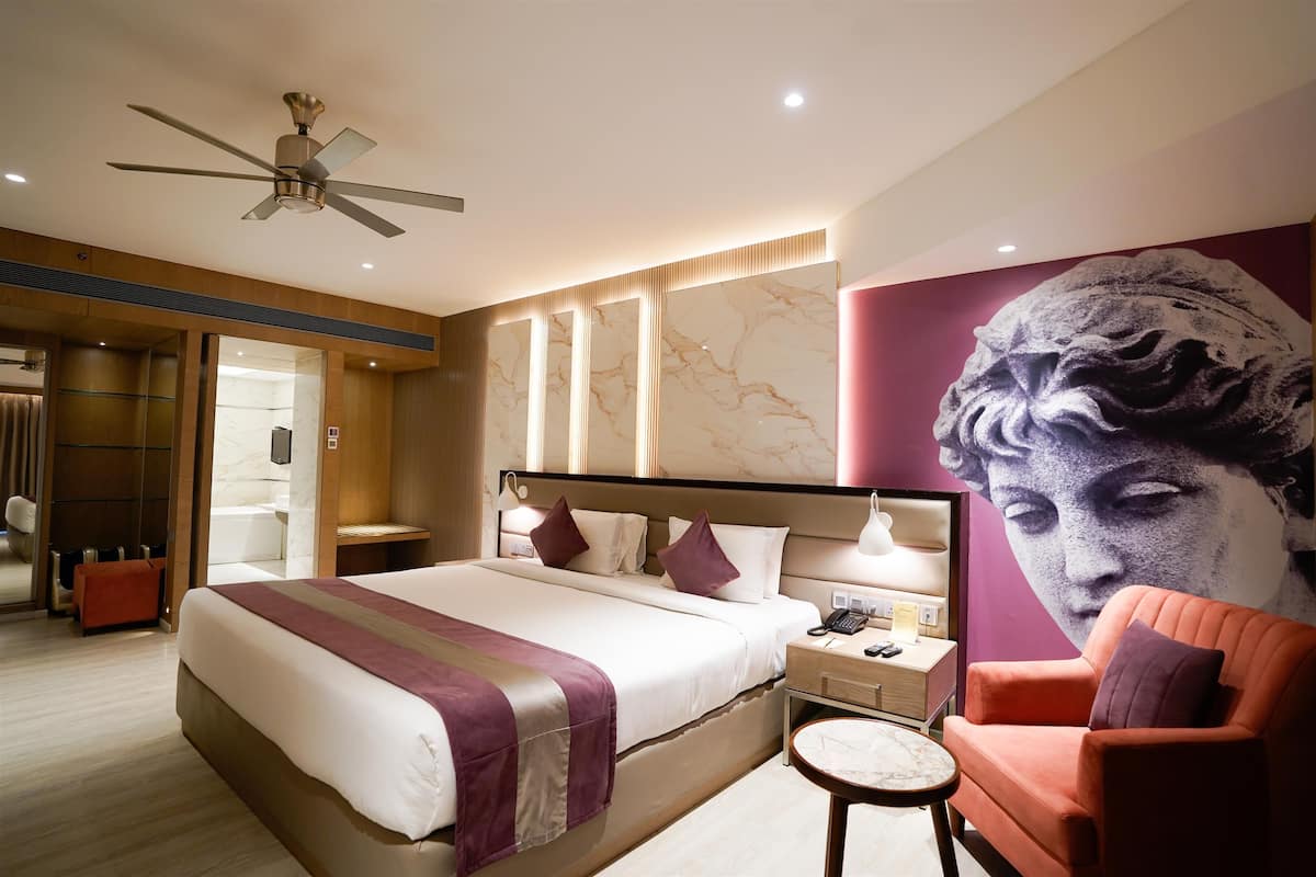 Una habitación de hotel moderna con una cama grande, una mesita de noche, una silla y un ventilador de techo.