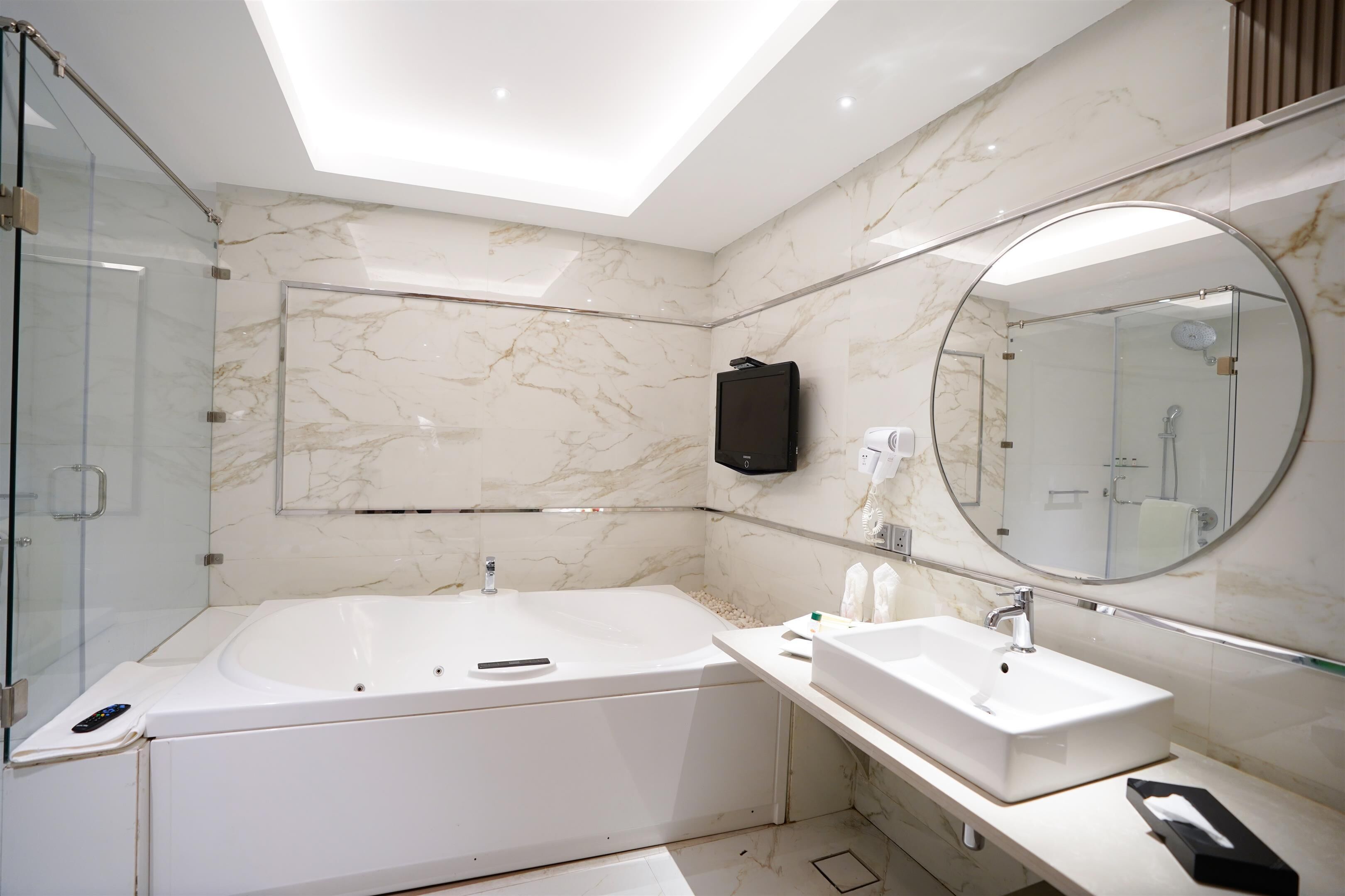 Une salle de bain moderne dotée d’une douche à parois de verre, d’une grande baignoire sur pieds et d’un meuble-lavabo avec miroir.