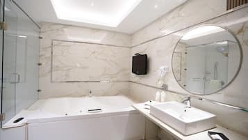 Une salle de bain moderne dotée d’une douche à parois de verre, d’une grande baignoire sur pieds et d’un meuble-lavabo avec miroir.