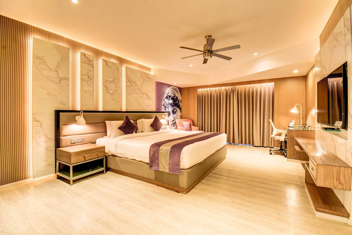 Una habitación de hotel moderna con una cama grande, un escritorio y una televisión.
