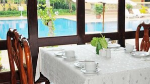 A dining area with a table set for two, overlooking a swimming pool. - Angkor Hotel (Siem Reap)