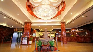 A lobby with a large statue, a chandelier, and a reception desk. - Angkor Hotel (Siem Reap)