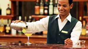 A bartender pouring a drink into a glass at a bar. - Angkor Hotel (Siem Reap)