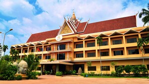 A multi-story hotel with a traditional architectural style, featuring a prominent entrance with a decorative facade and a tiled roof. - Angkor Hotel (Siem Reap)
