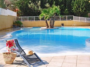 Una piscina con sillas de descanso y una palmera.