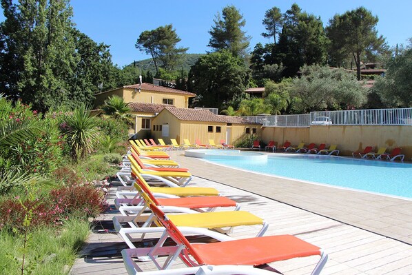 A poolside area with rows of sun loungers and a building in the background.