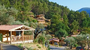 A wooden cabin with a balcony, surrounded by dense forest and hills. - Lagrange Vacances Les Cottages Varois (Sollies-Toucas)