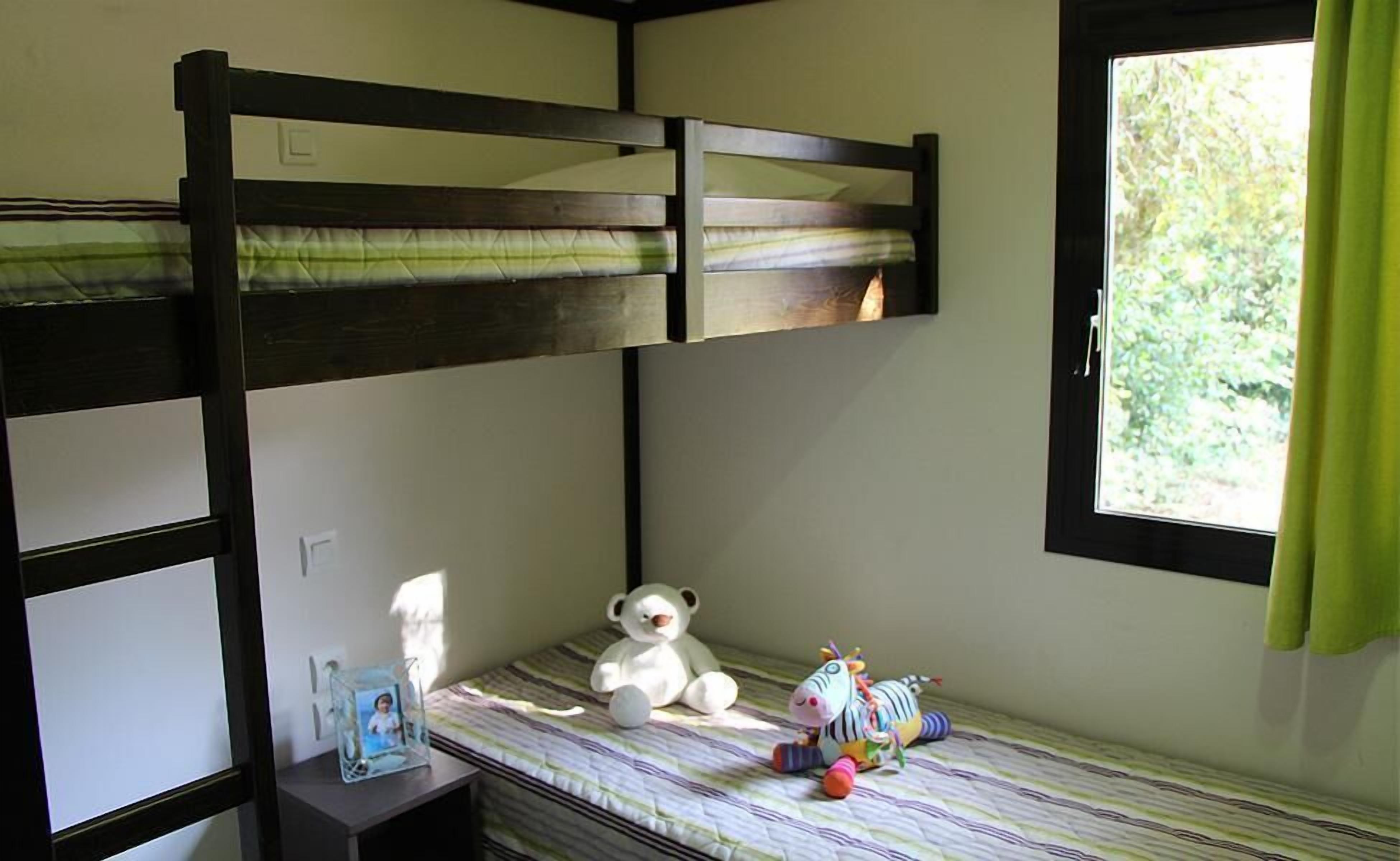 Ein Schlafzimmer mit Etagenbetten, einem Fenster, einem Teddybären und einem Zebratier auf dem Bett.