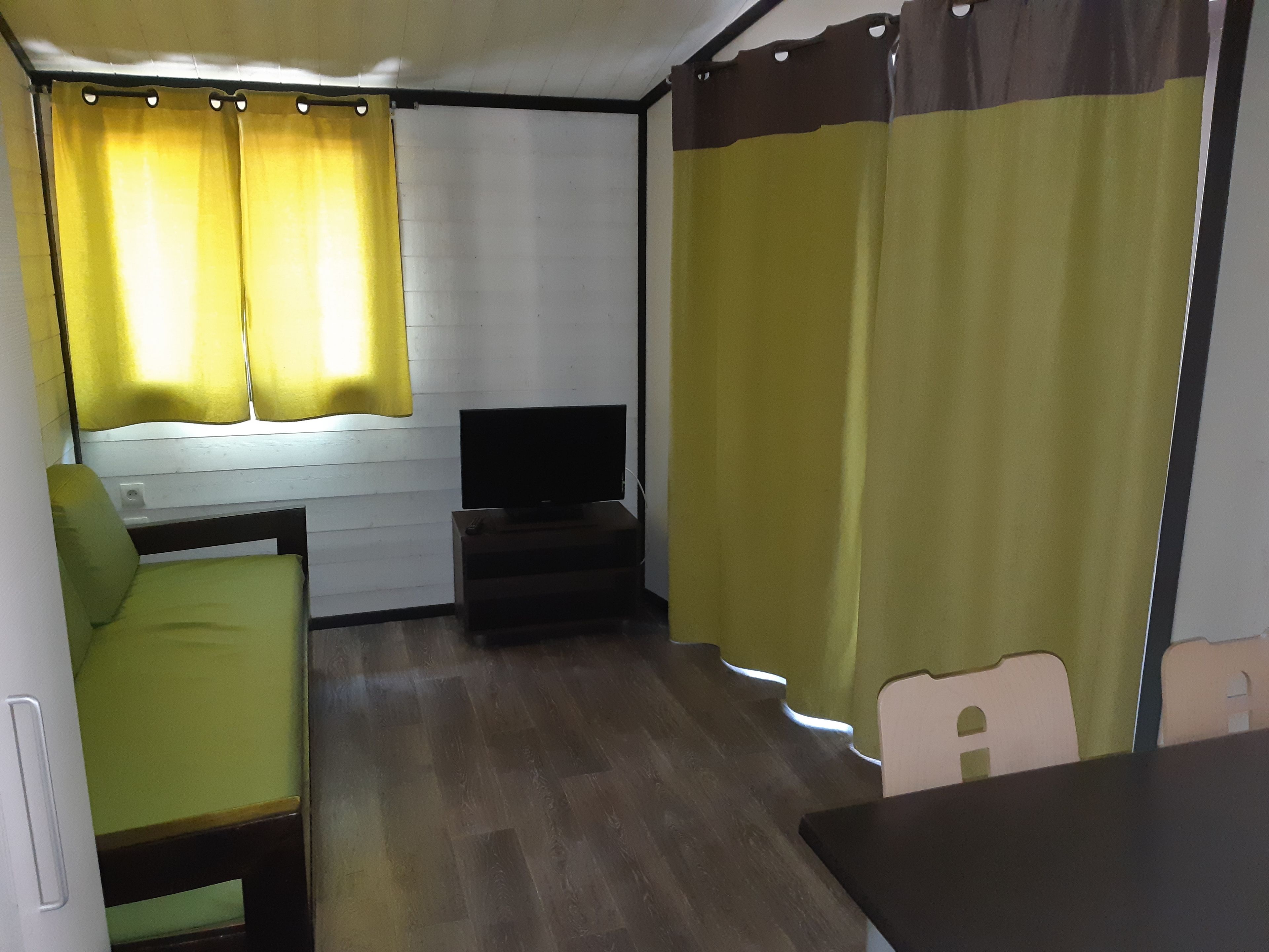 Um espaço compacto para viver, com televisão, uma mesinha e um sofá.