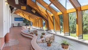 A modern interior with a curved pathway, potted plants, and a 'Welcome Home' sign. - Alpine Club (Schladming)
