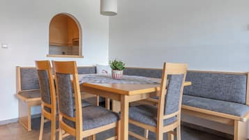 A dining area with a wooden table, four chairs, a bench, and a hanging light fixture.