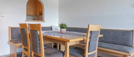 A dining area with a wooden table, four chairs, a bench, and a hanging light fixture.