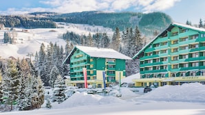 A hotel with multiple floors and a ski resort in the background. - Alpine Club (Schladming)