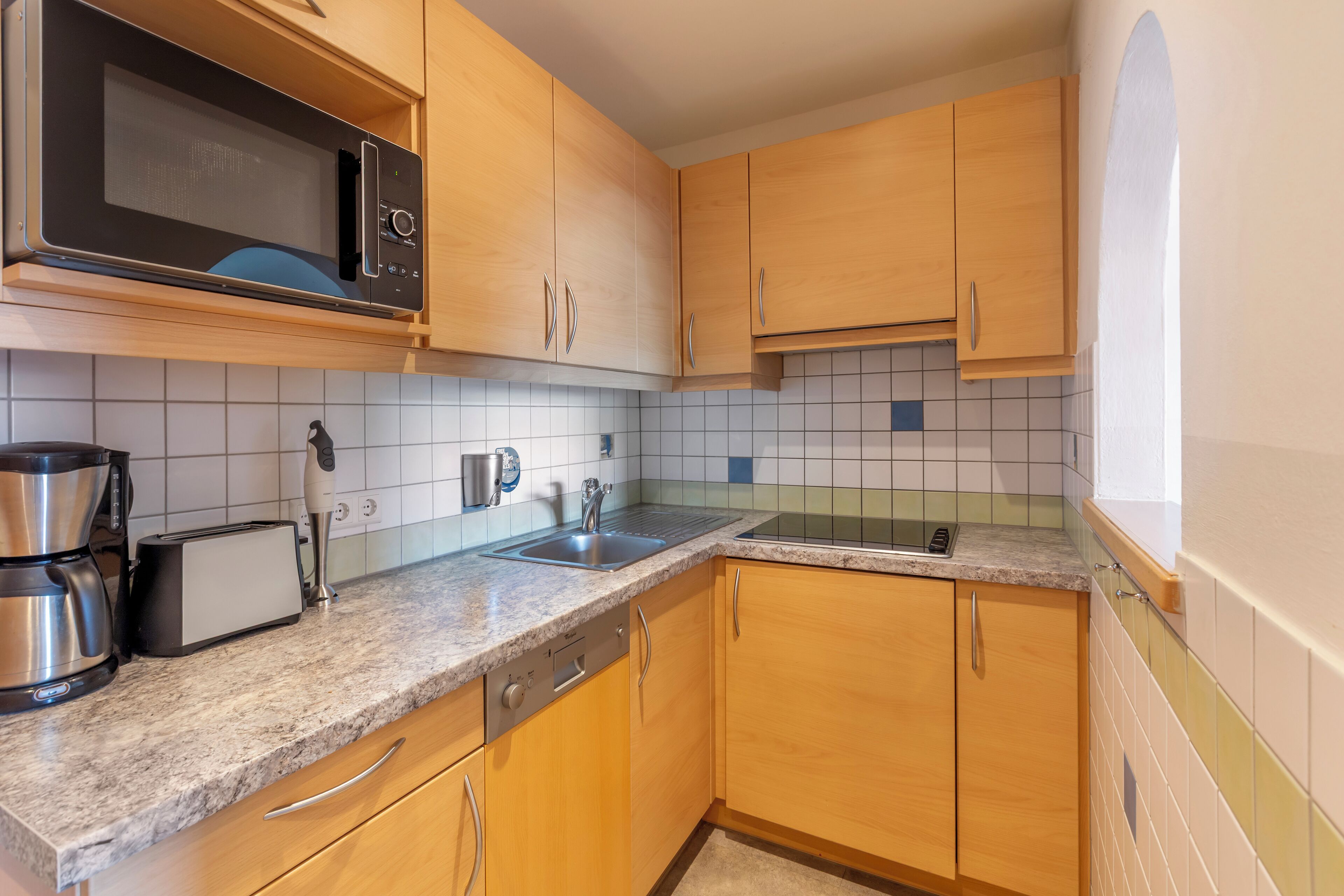 A kitchen with wooden cabinets, a microwave, a toaster, and a coffee maker.
