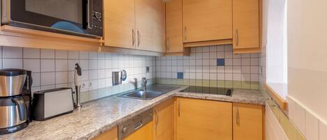 A kitchen with wooden cabinets, a microwave, a toaster, and a coffee maker.
