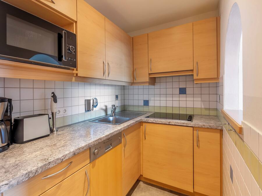 A kitchen with wooden cabinets, a microwave, a toaster, and a coffee maker.