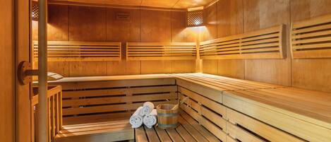 Una sauna con bancos de madera y un cubo de toallas.