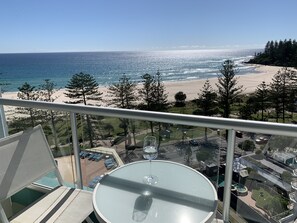 A balcony with a glass table and chairs, overlooking a beach and ocean. - Ocean Plaza Resort (Coolangatta)