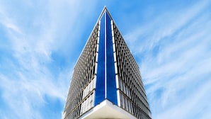 Un rascacielos moderno con una fachada azul y blanca distintiva, que presenta un diseño tipo cuadrícula y un elemento vertical central.