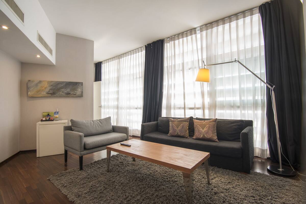Una sala de estar con un sofá, una mesa de centro, una lámpara y un cuadro en la pared.