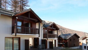 Ein modernes Mehrgeschosshaus mit Balkonen, großen Schiebeglasfenstern und einem Rasengrundstück.