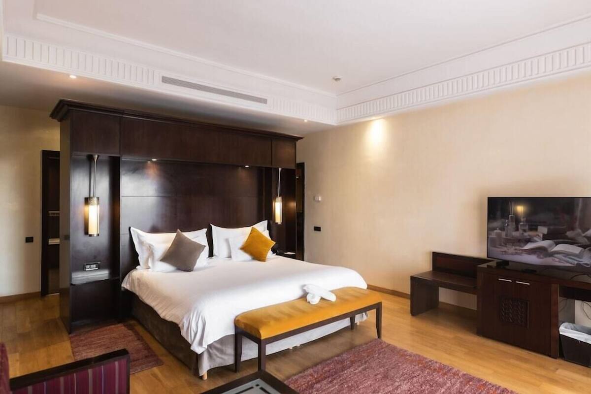 Una habitación de hotel moderna con una cama grande, un televisor y un banco de madera.