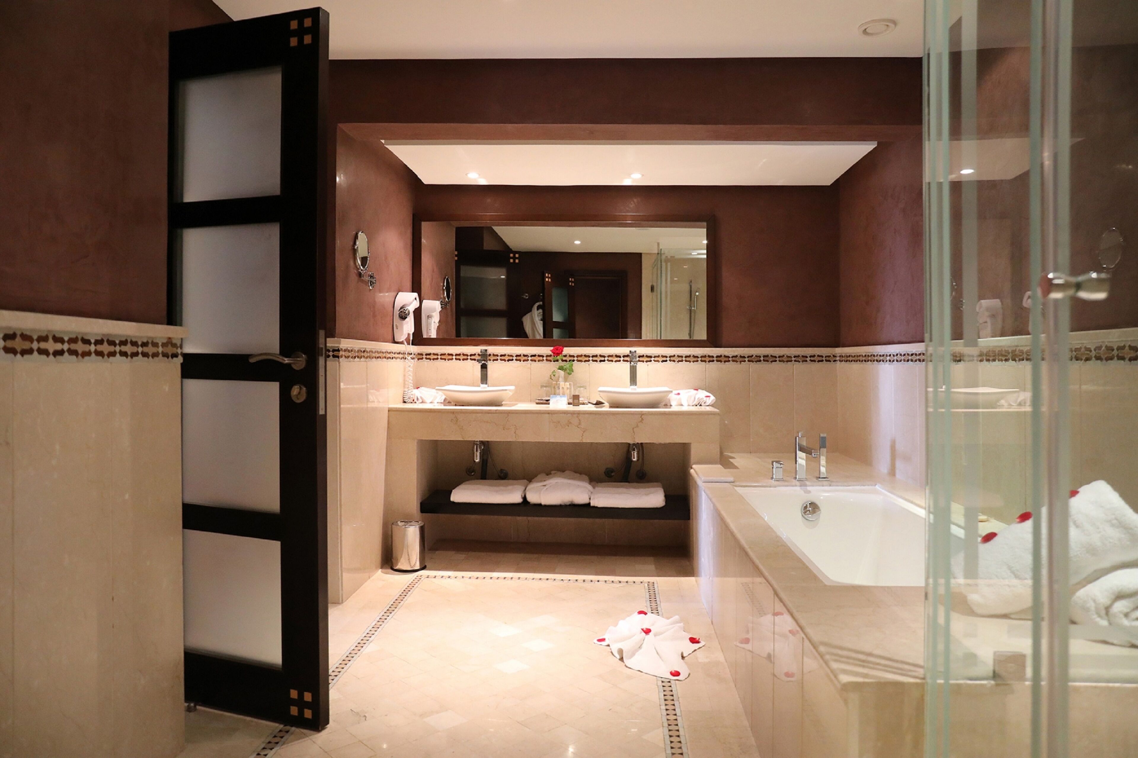 Un baño con un espejo grande, dos lavamanos, una bañera y un box de ducha de vidrio.