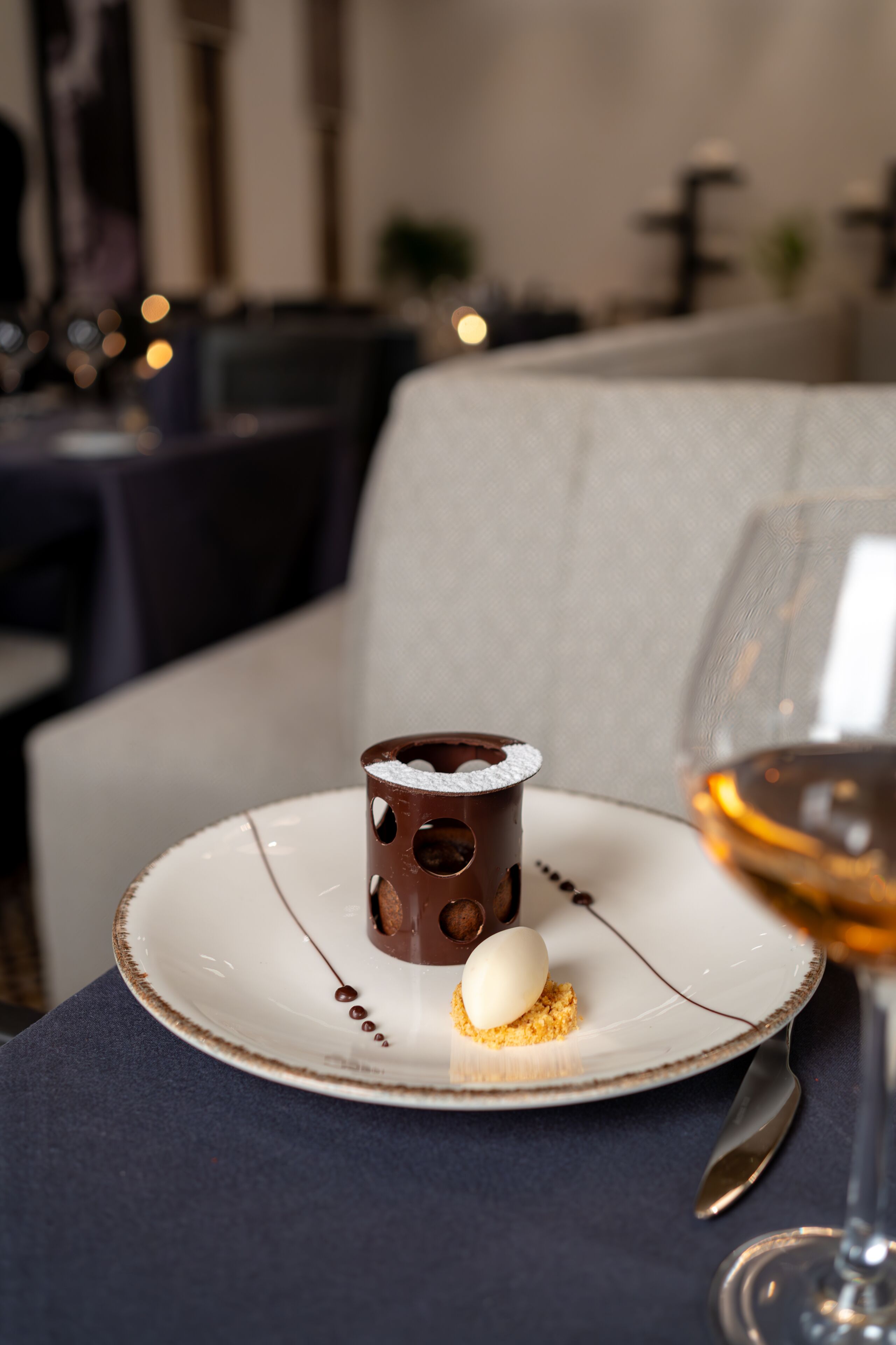 Une assiette à dessert avec une coupe au chocolat, une boule de glace et un petit gâteau, le tout posé sur une table.