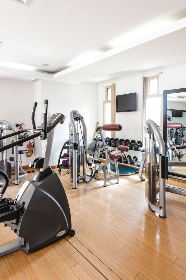 Un gimnasio con máquinas de cardio, pesas y mancuernas.