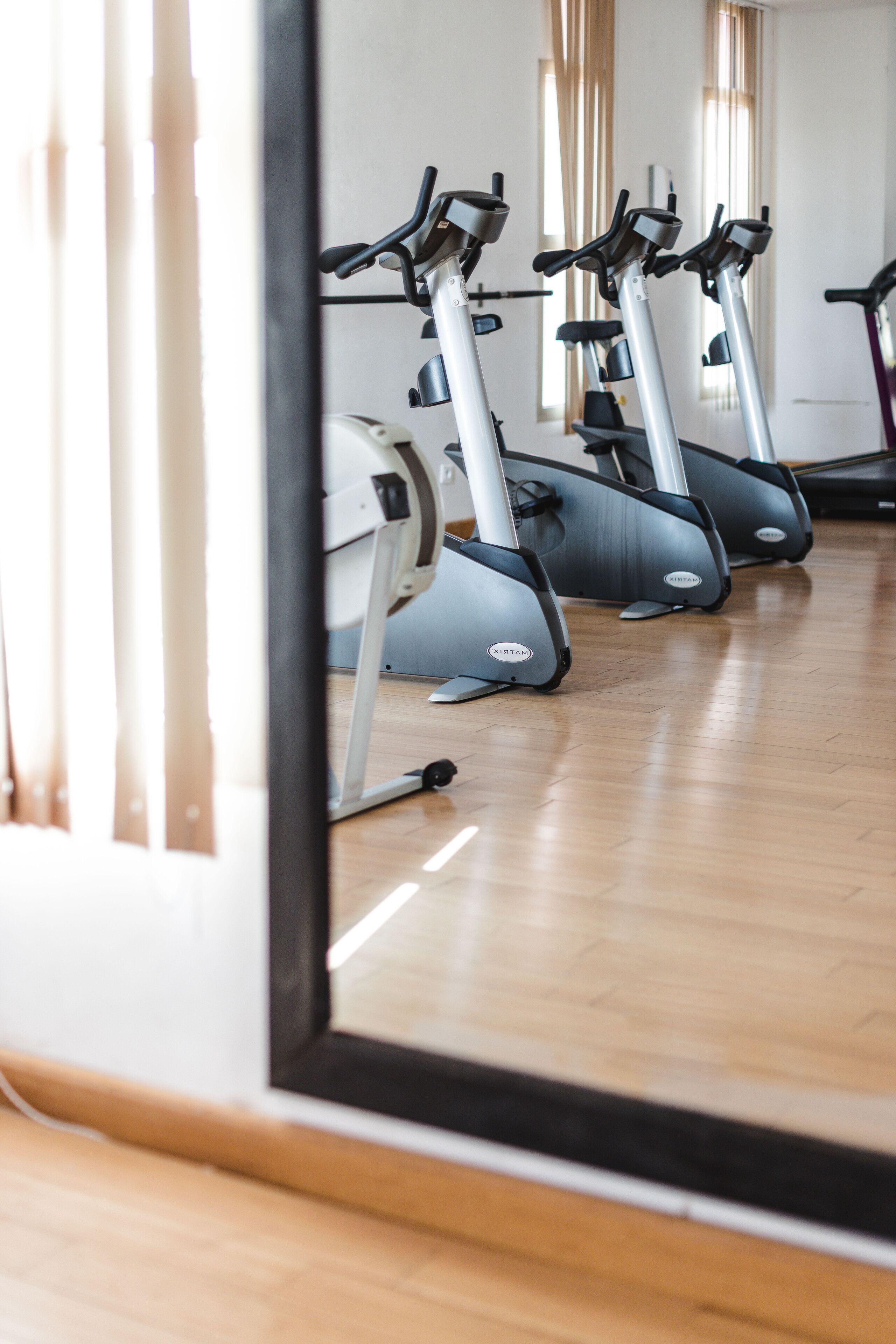 A row of stationary bikes in a room with wooden flooring.