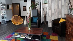 A modern living room with a wooden coffee table, a colorful rug, and a black leather sofa.