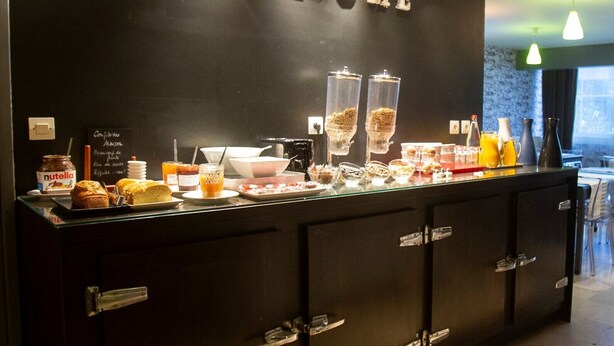 A reception area with a black counter displaying various breakfast items, a 'WELCOME' sign, and a view of the outside.