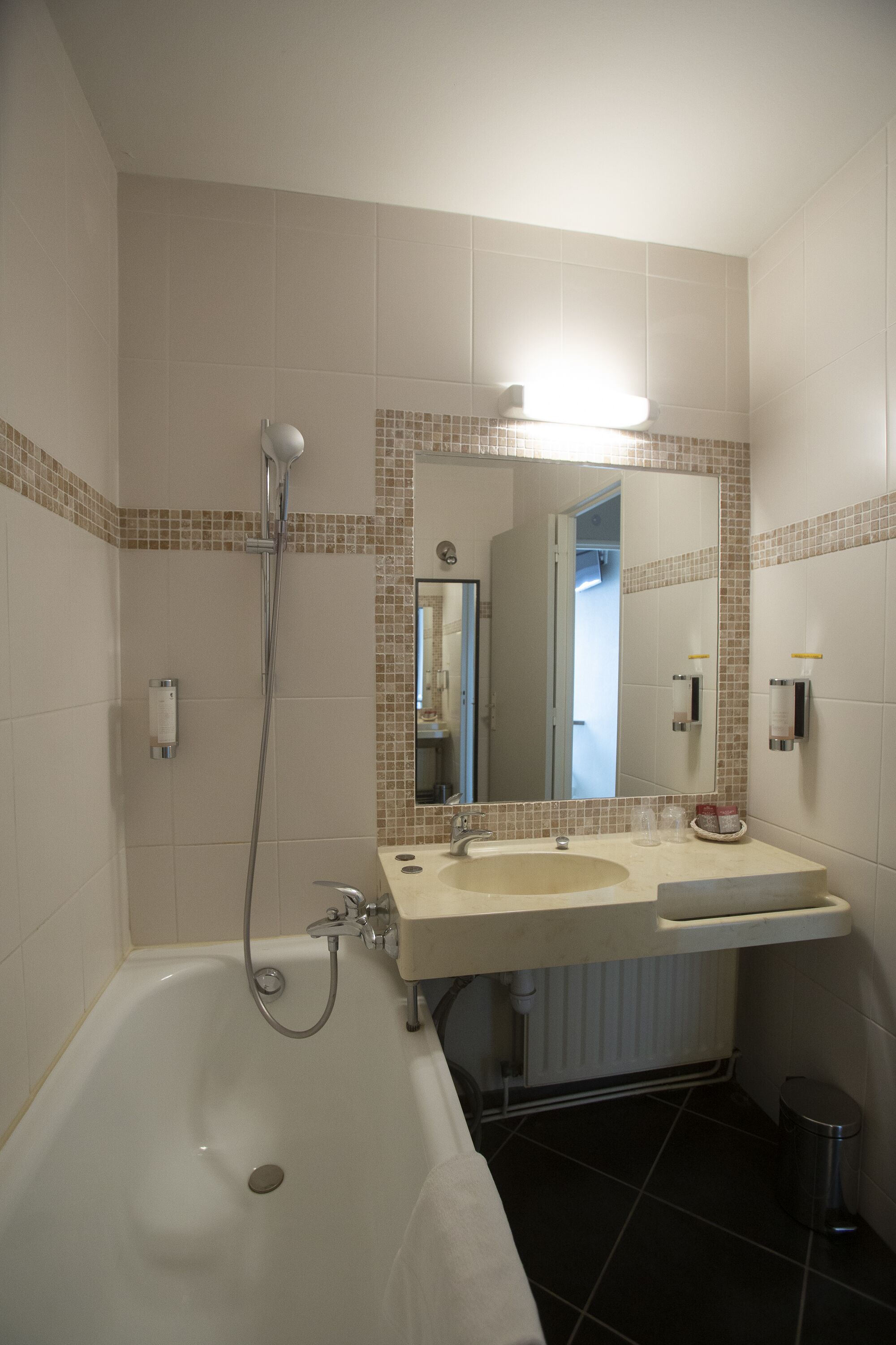 Un baño con bañera, dos lavamanos, un espejo y un inodoro.