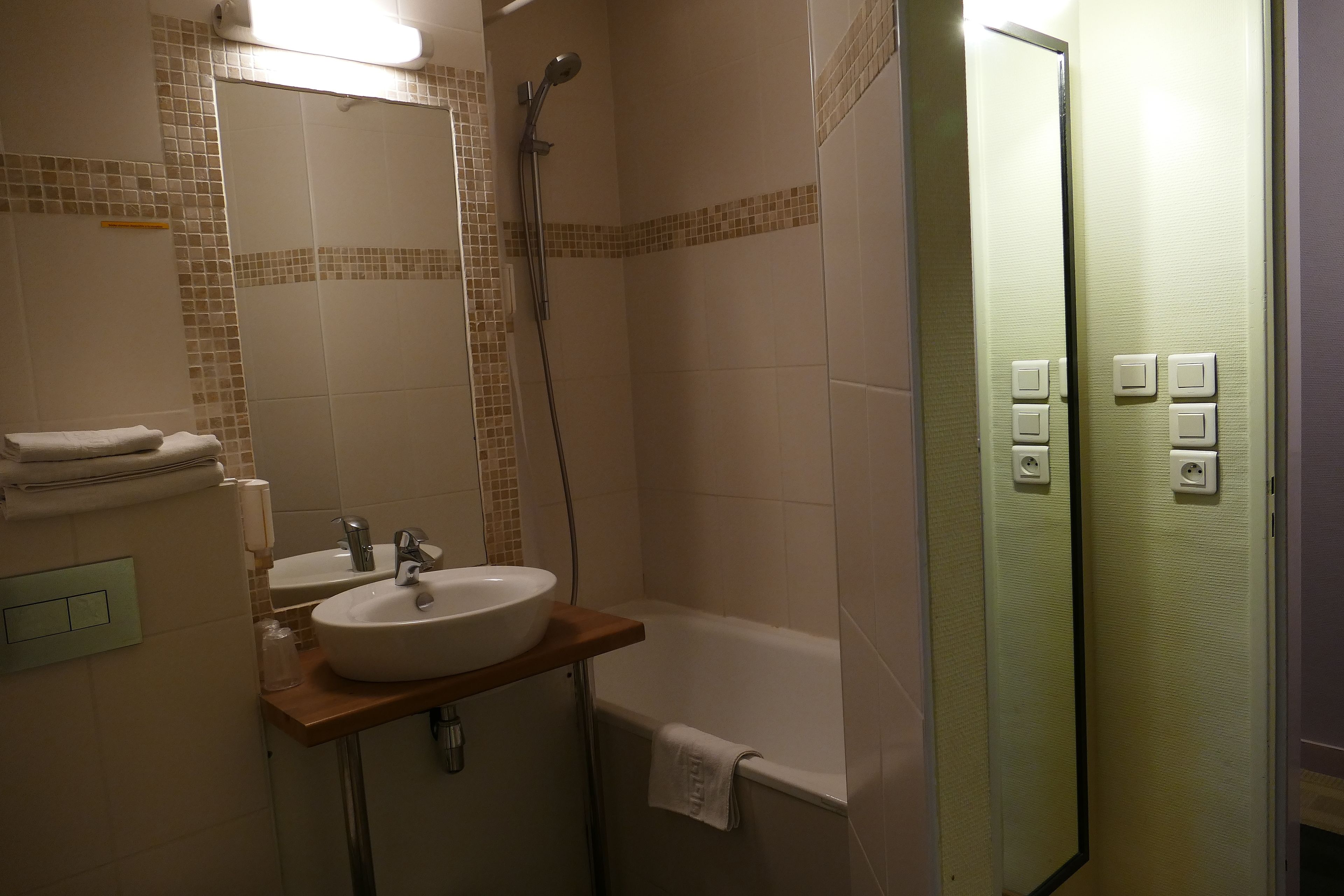 Een badkamer met een wastafel, spiegel en douche.