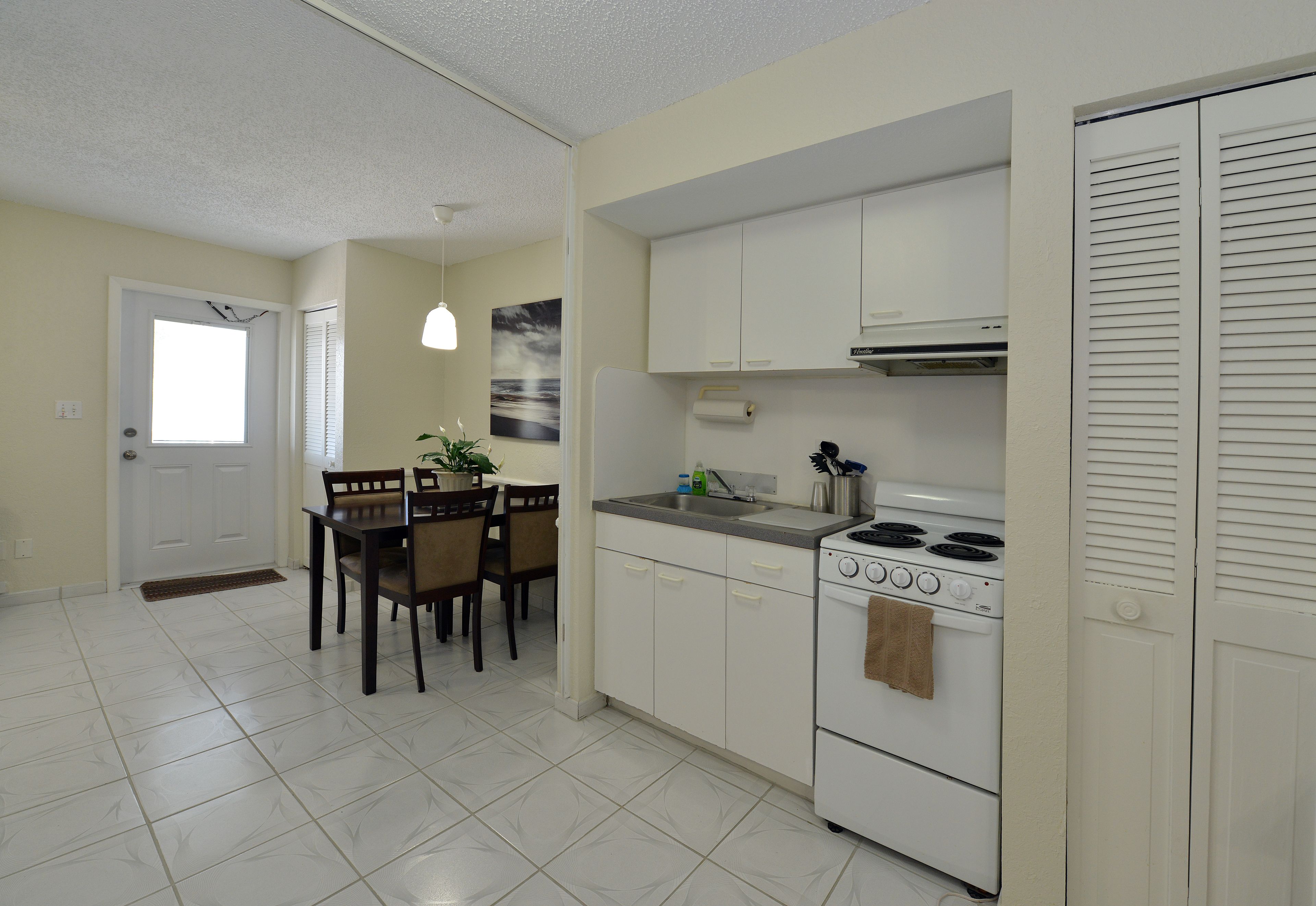 A kitchen with white cabinets, a stove, and a dining area with a table and chairs.