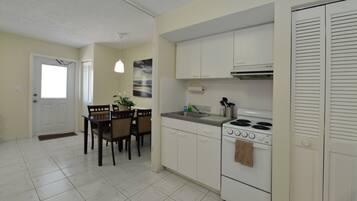 A kitchen with white cabinets, a stove, and a dining area with a table and chairs.