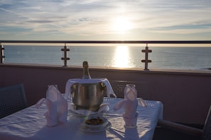 A table set with a bottle, a bowl of nuts, and folded napkins on a balcony overlooking the sea. - Hotel Quarteirasol (Loulé)