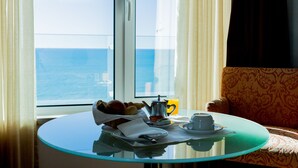 Une table de petit-déjeuner avec vue sur la mer, une cafetière et une tasse de café.