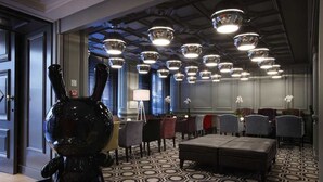 Un vestíbulo de hotel con piso de diseño geométrico, varias zonas de estar y una gran escultura negra.