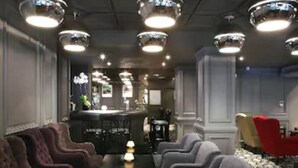 Un vestíbulo de hotel con una larga mesa, varios sillones y una zona de bar.