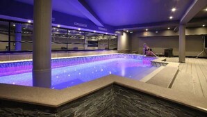 Una piscina interior con borde de piedra y una persona sentada al borde.