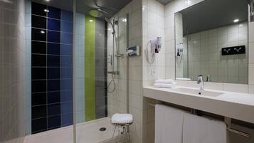 A modern bathroom with a glass-enclosed shower, a white sink, and a large mirror.