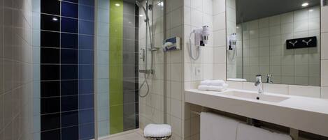 A modern bathroom with a glass-enclosed shower, a white sink, and a large mirror.
